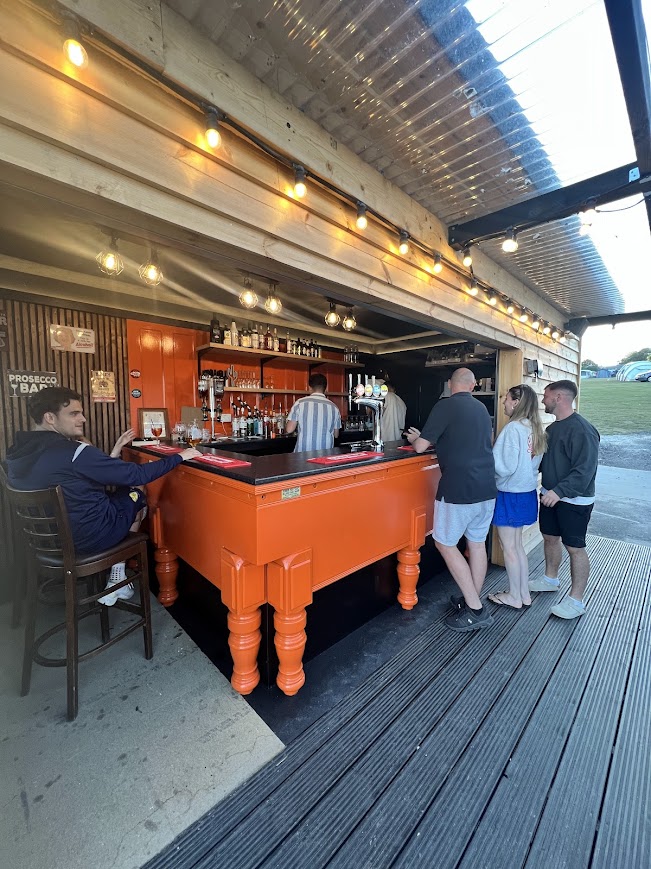 Customers standing at Sam's Bar at Kingsdown Camping